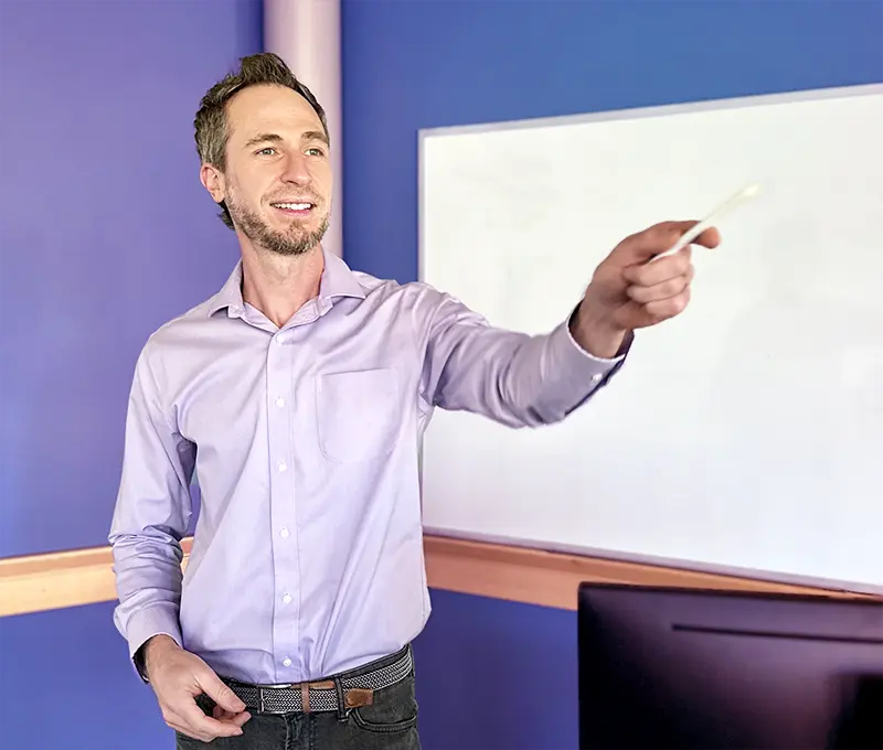 Man standing in classroom, pointing at student